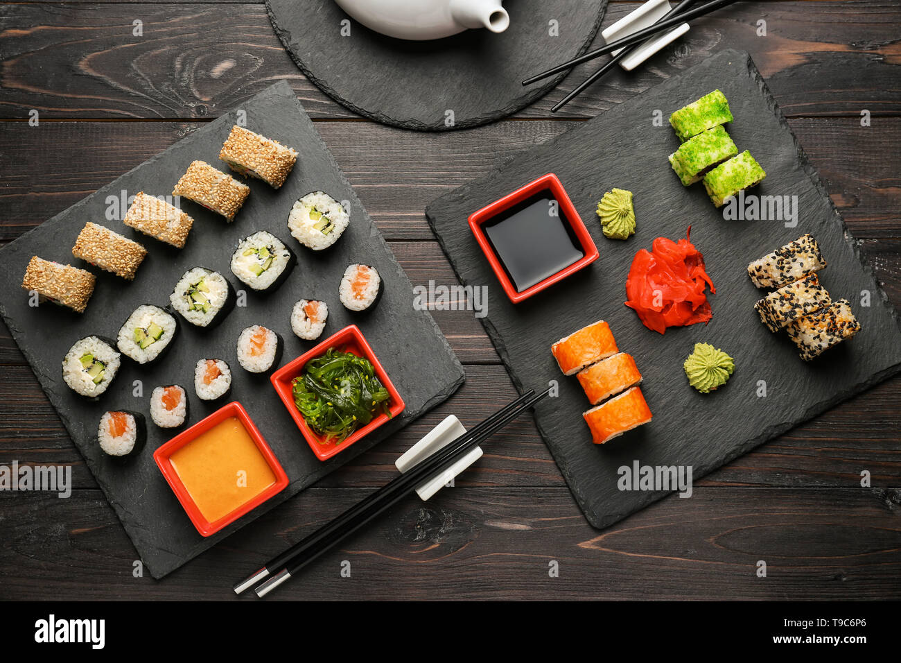 Schiefer Platten mit verschiedenen Sätzen von Sushi am Holztisch Stockfoto