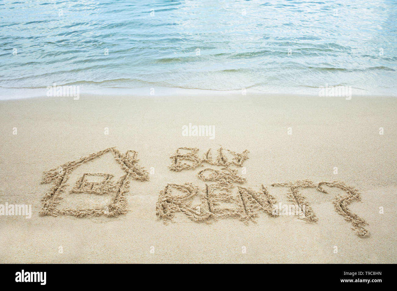 Kaufen oder Mieten Text mit gezogenen Haus auf Sand in der Nähe des Meer am Strand Stockfoto