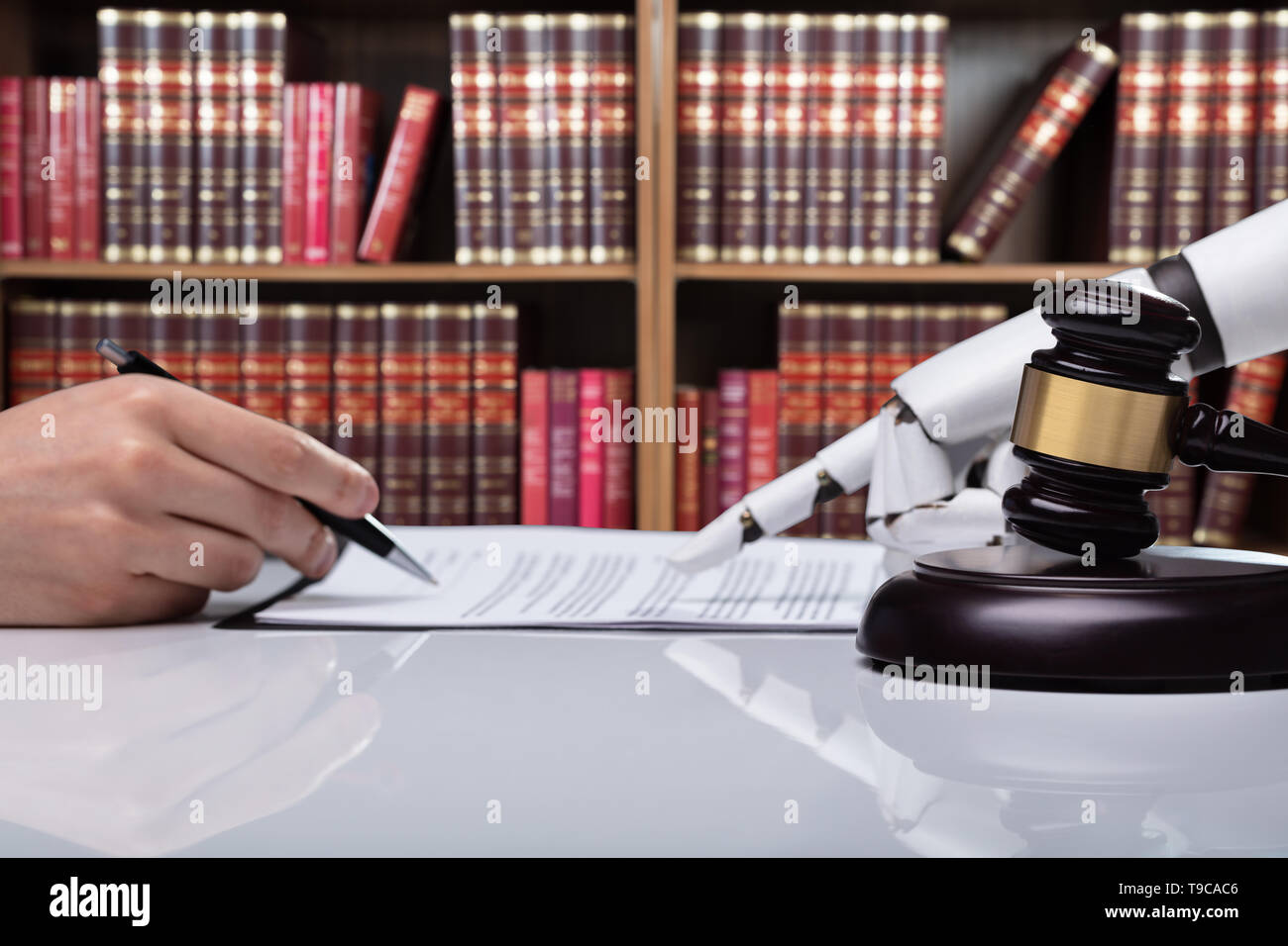 Roboterhand Unterstützung der Person, die für die Unterzeichnung dieses Dokuments reflektierende Schreibtisch Im Gerichtssaal Stockfoto