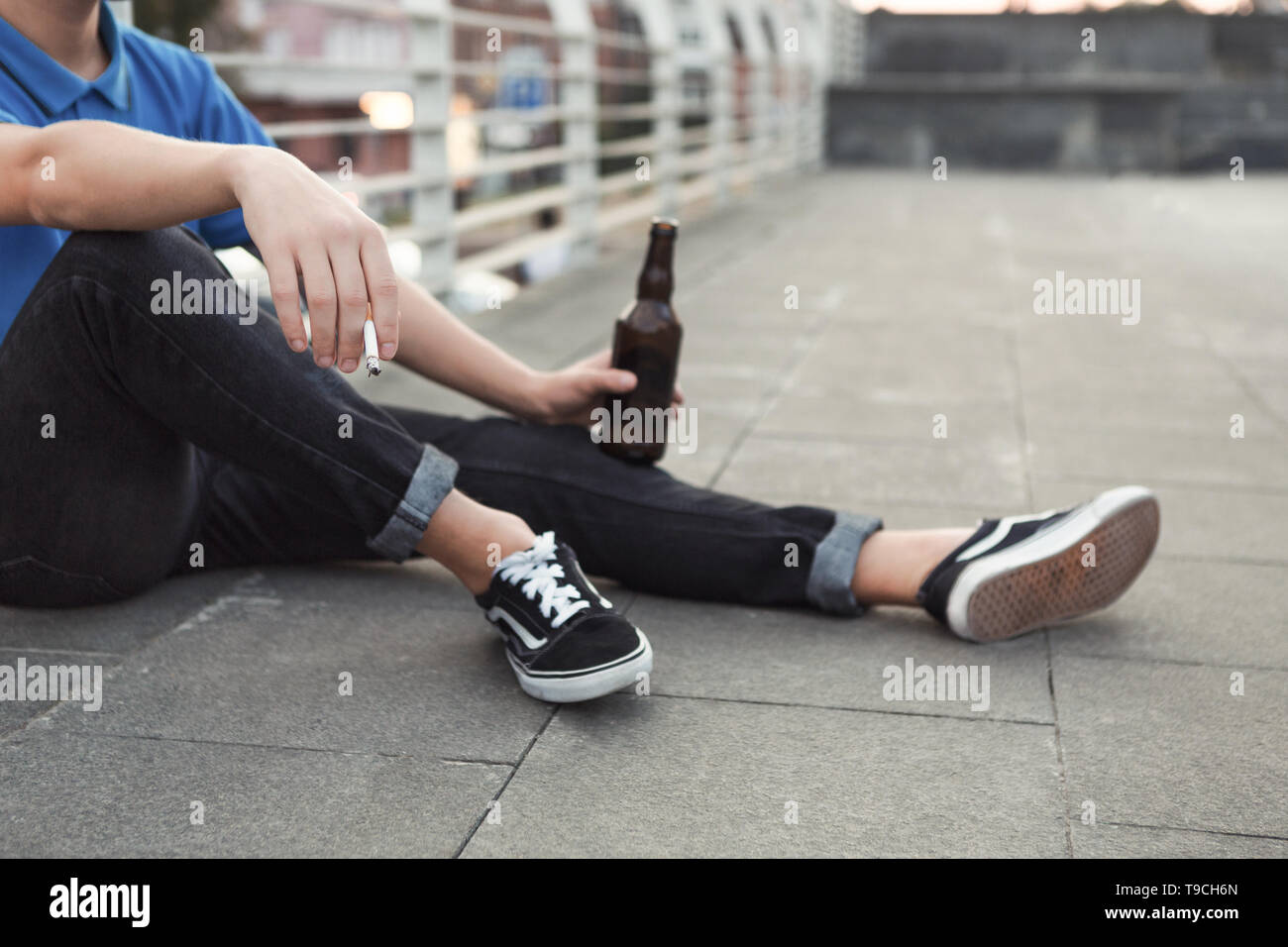 Teen guy rauchen Zigaretten und Bier trinken, sitzen nur Stockfoto