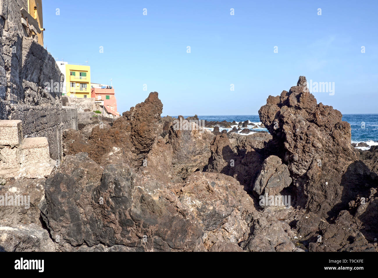 Die bizarr geformten schwarzen vulkanischen Steinen am Ufer des Atlantiks auf der Punta Brava in Teneriffa. Zwei bunte Häuser sind auf der linken Seite, ein p Stockfoto