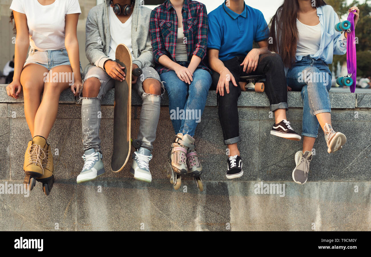 Aktive diverse Freunde sitzen in städtischen Skatepark mit skateboards Stockfoto