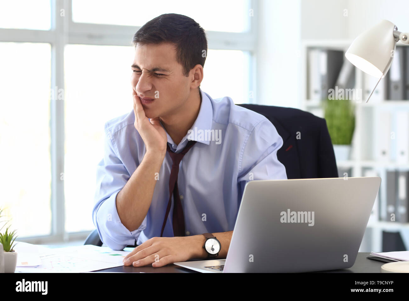 Junge Unternehmer leiden unter Zahnschmerzen im Büro Stockfoto