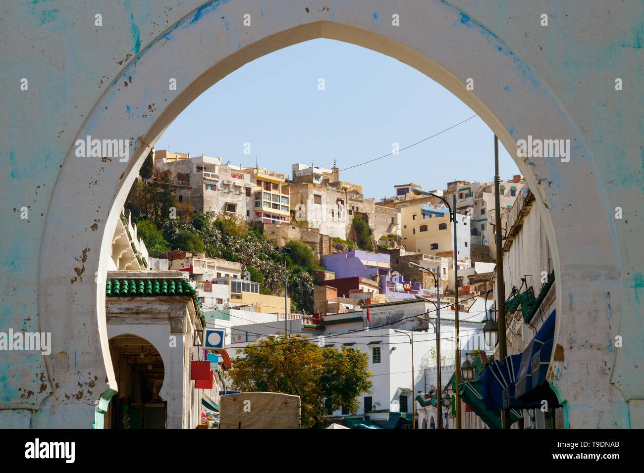 Hill mit Häusern und Straßen von Moulay Idriss Zerhoun an einem sonnigen Tag, gesehen durch das Eingangstor der Stadt, Marokko. Stockfoto