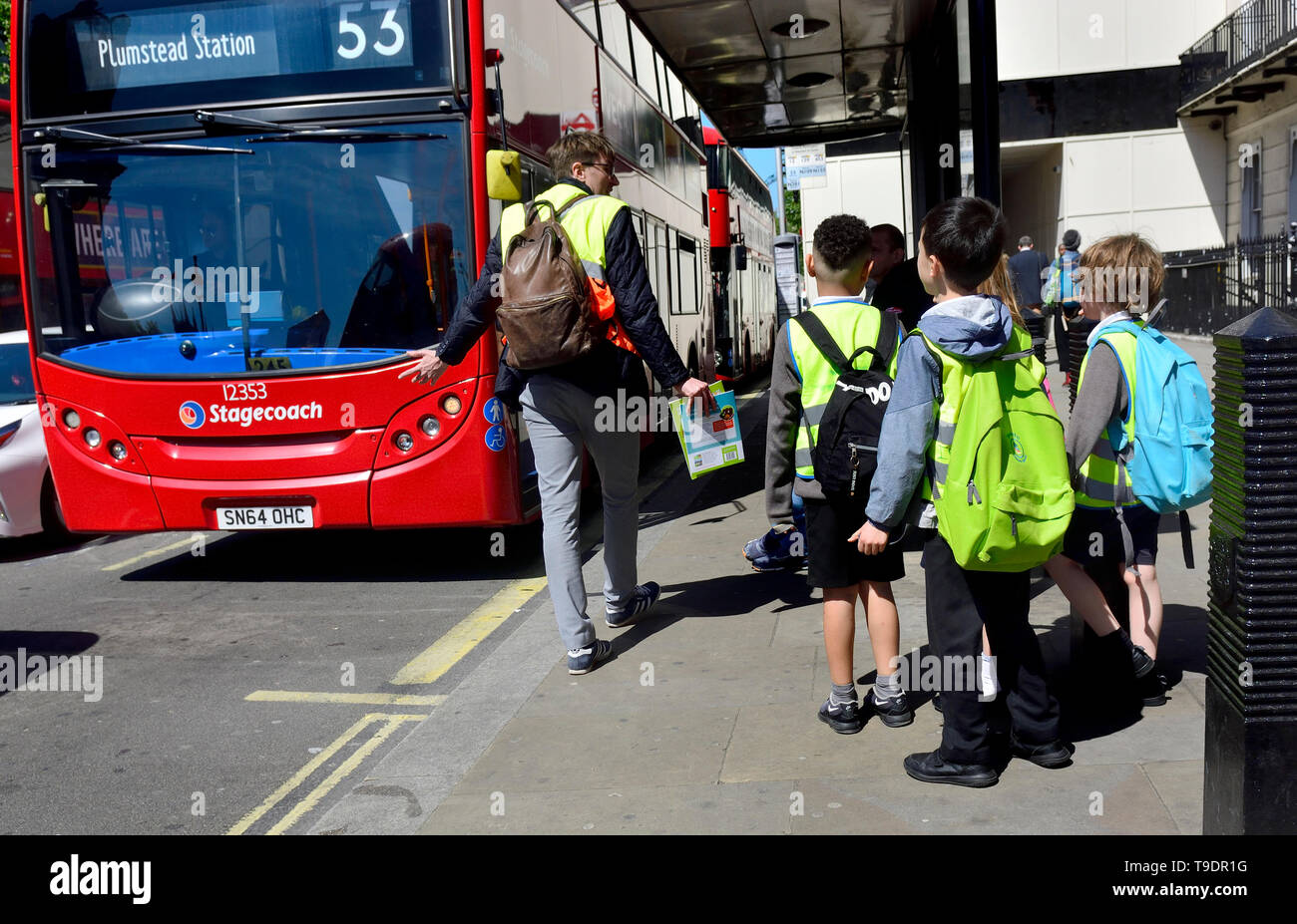 London, England, UK. Gruppe von Schulkindern warten auf einen Bus zu erhalten Stockfoto