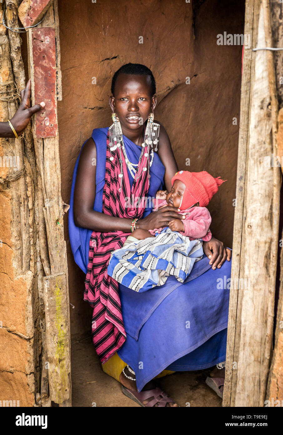 MASAI DORF, KENIA - Oktober 11, 2018: Unindentified afrikanische Frau mit einem Baby, die traditionelle Kleidung in Masai Stamm, Kenia Stockfoto