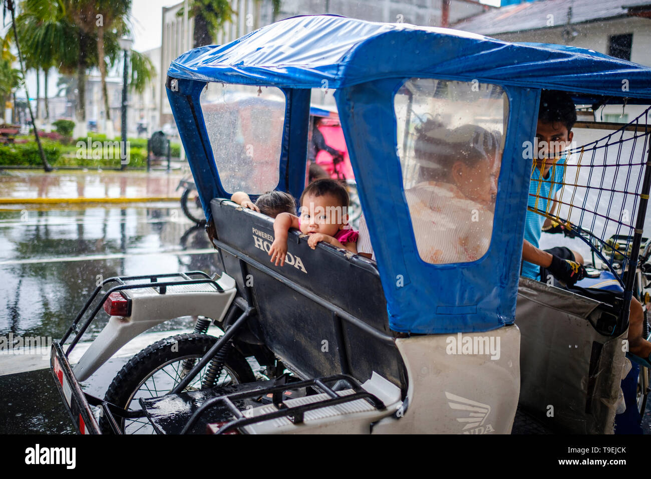 Kleines Mädchen auf der Suche aus dem Mototaxi Fenster bei Regen auf Iquitos, Provinz Maynas, Loreto Region, Peru Stockfoto