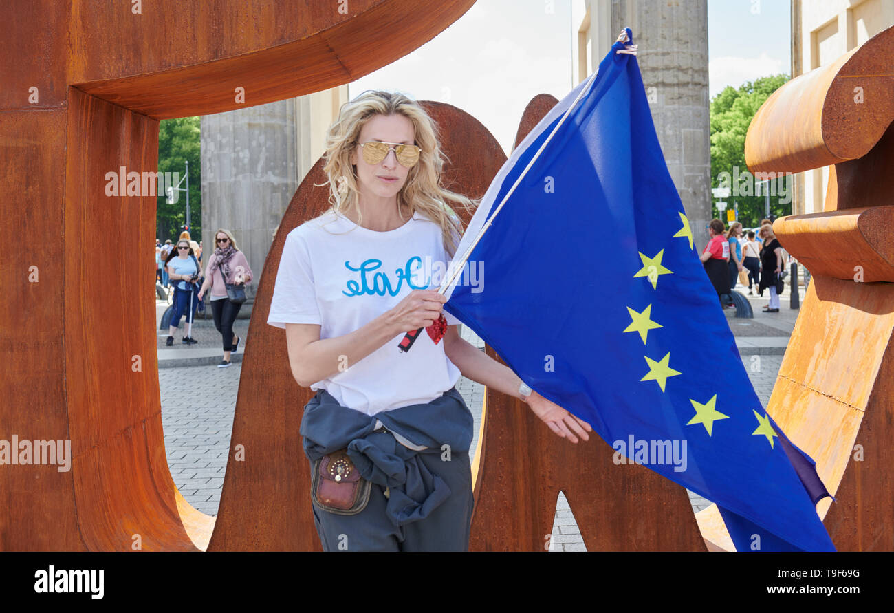 Berlin, Deutschland. 18 Mai, 2019. Die Künstlerin Mia Florentine Weiss steht vor ihrer Skulptur 'lieben' vor dem Brandenburger Tor und hält die europäische Flagge. Quelle: Annette Riedl/dpa/Alamy leben Nachrichten Stockfoto