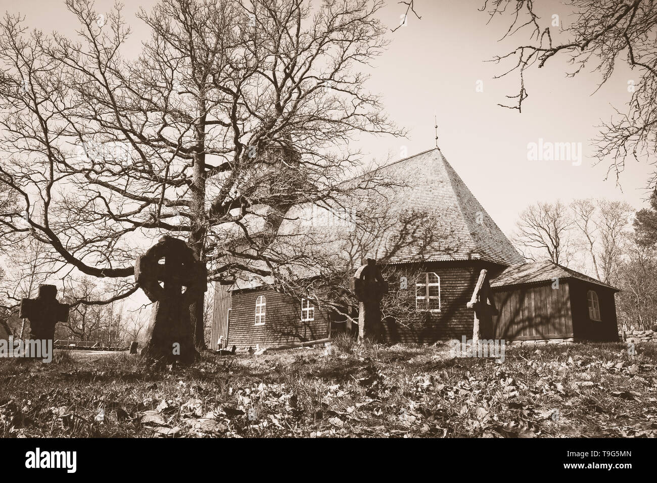Die traditionelle schwedische Kirche aus Holz, die auf dem alten Friedhof. Einige Steinkreuze sind sichtbar. Bild im alten Stil Farben. Stockfoto