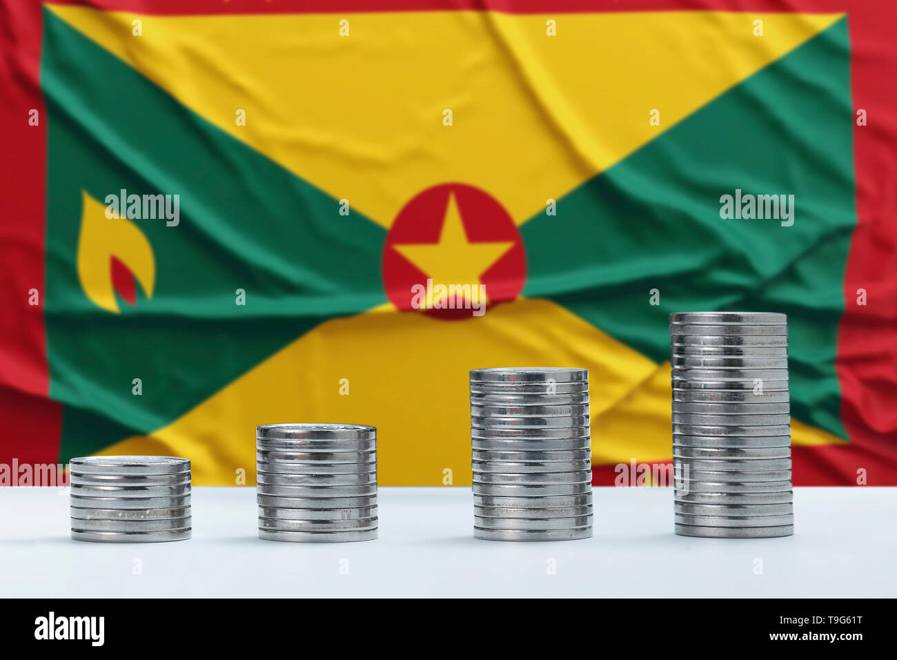 Faltige Grenada Flagge im Hintergrund mit Reihen von Münzen, die für Finanzen und Business Konzept. Spart Geld. Stockfoto