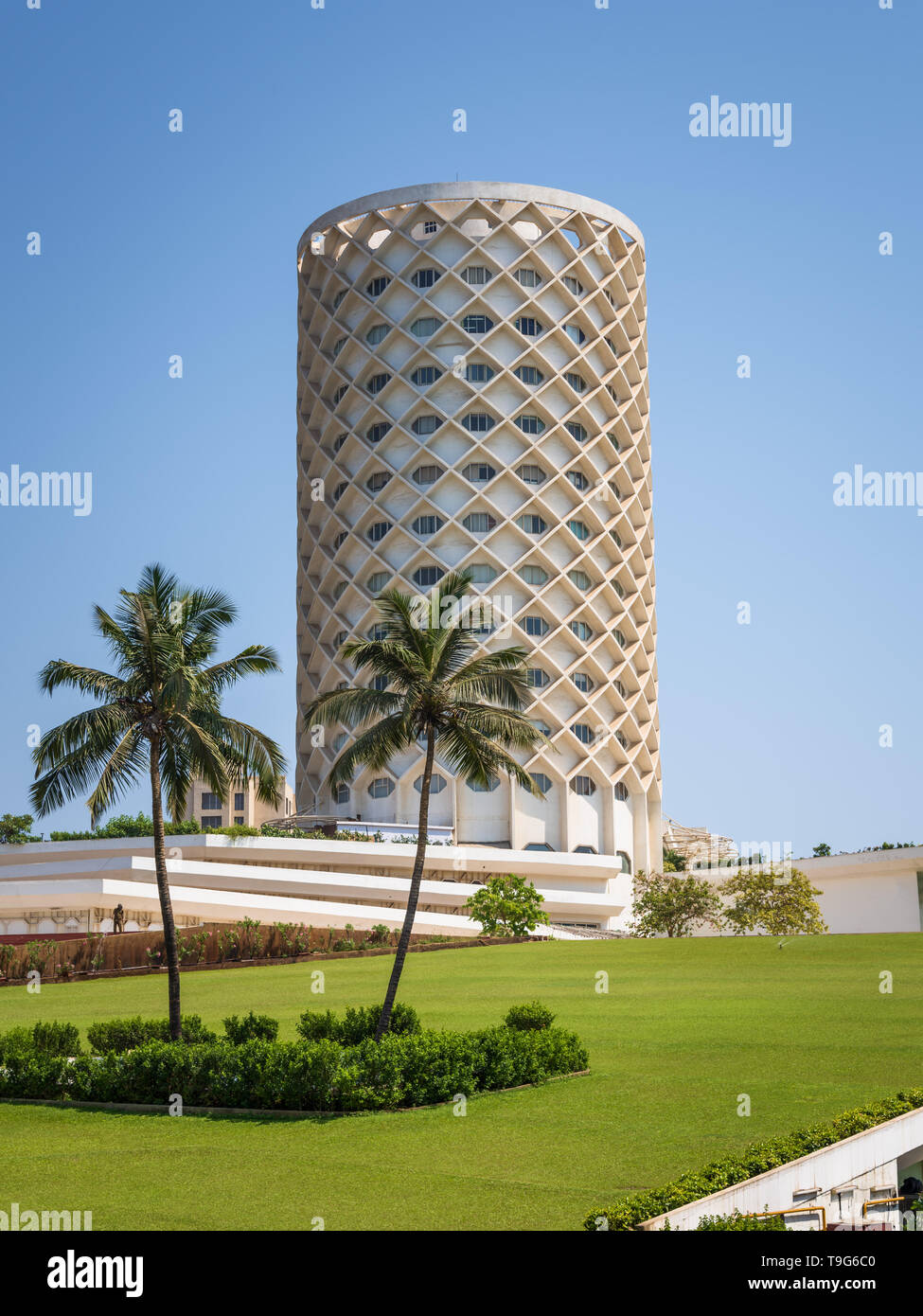 Der ikonische zylindrische Gitterturm des Nehru Centre in Mumbai, Indien, gesehen an einem klaren Tag hinter Palmen und einem gepflegten grünen Rasen. Stockfoto