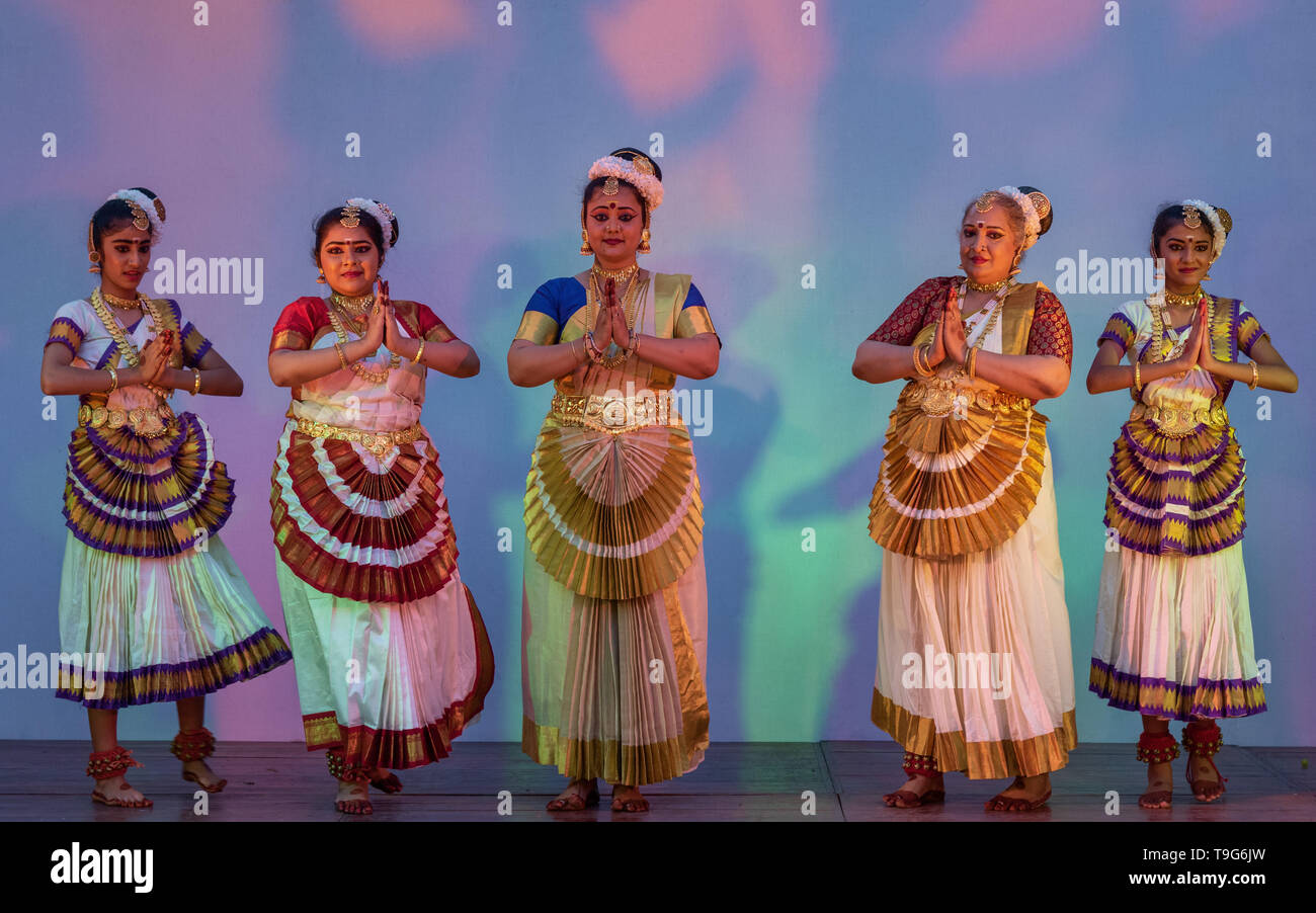 Eine Gruppe von fünf Mohiniyattam-Tänzerinnen führt einen südindischen klassischen Tanz in traditioneller weißer und goldener Kasavu-Tracht auf der Bühne auf. Stockfoto