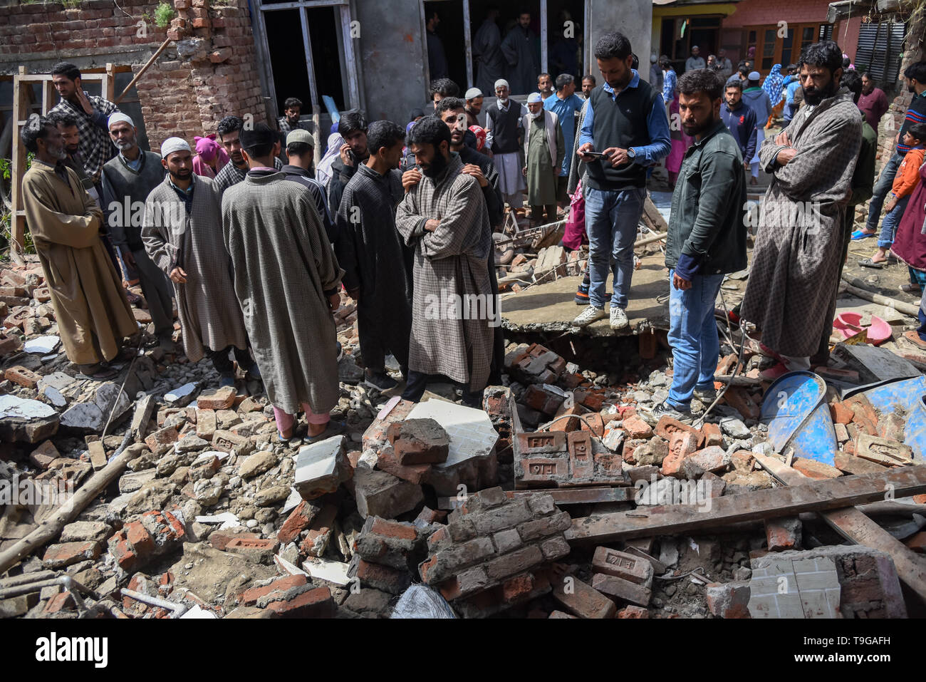 Kaschmir Dorfbewohner werden gesehen, um eine teilweise beschädigten Haus versammelt nach einer Schießerei in Pulwama, südlich von Srinagar. Vier kaschmirischen Rebellen waren am Samstag in zwei separaten Schießereien in Jammu und Kaschmir von Pulwama und Baramulla Bezirke getötet. Stockfoto