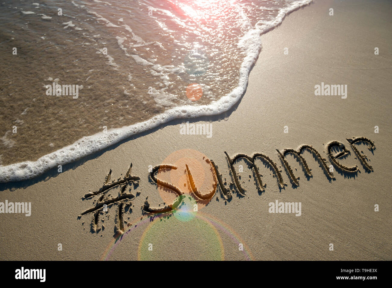 Moderne Nachricht für den Sommer mit einem Social Media - freundliche hashtag in glatten Sand geschrieben mit ankommenden Welle auf den Strand Stockfoto