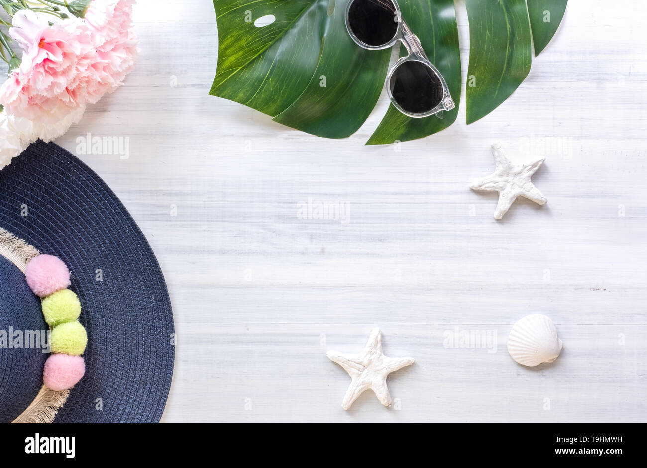 Blick von oben auf die Summer Blue weibliche Hut mit Sonnenbrille und Shell und Star fisch Dekoration auf weißem Holz Tisch. Sommer Urlaub Stockfoto