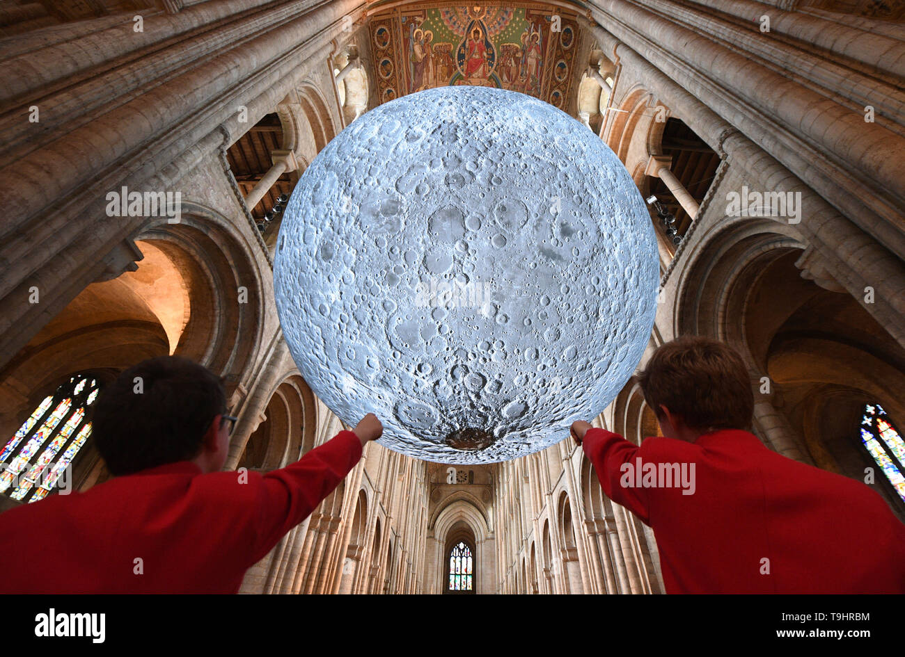 Chorknaben ansehen Luke Jerram's 'Museum der Installation der Mond' an die Kathedrale von Ely in Cambridgeshire. Die 7 Meter Durchmesser Replik der Mond ist die Hauptattraktion in der Kathedrale Science Festival", die Begrenzung des Himmels", die zum 50. Jahrestag der ersten Mondlandung feiert. Stockfoto