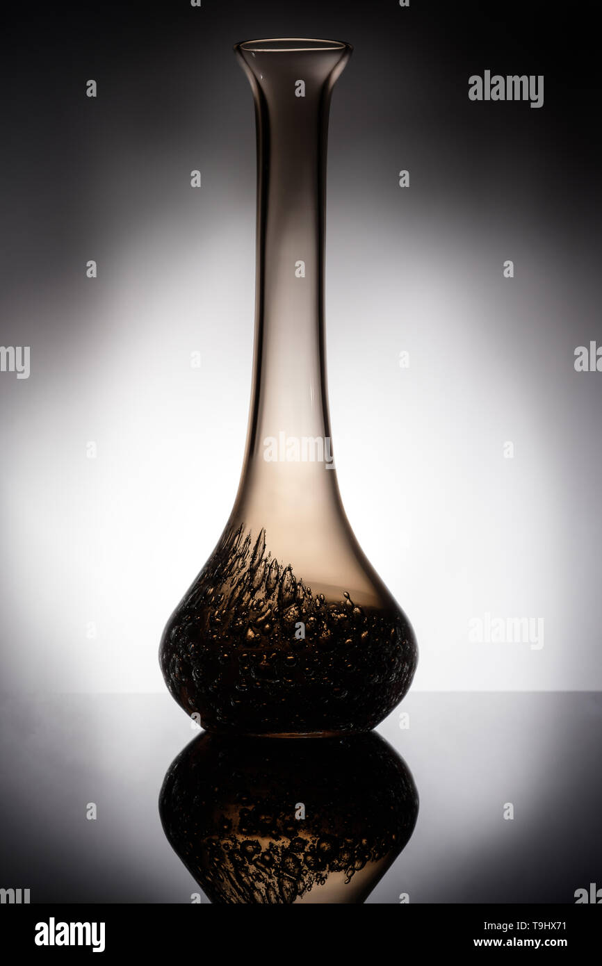 Glas Vase in Hintergrundbeleuchtung mit Reflexion im Hochformat Stockfoto