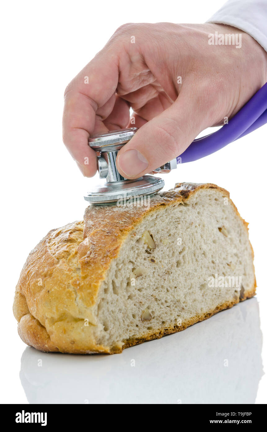 Männliche hand Stethoskop auf ein Laib Brot, Buchweizen mit Walnüssen. Auf weissem Hintergrund. Stockfoto