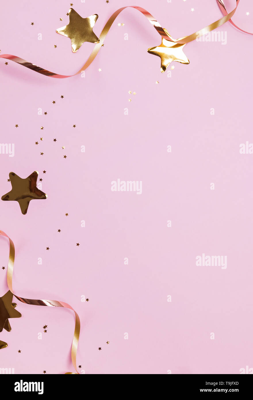 Goldene Dekor sternförmigen Konfetti und Bänder auf Pastell rosa Hintergrund isoliert. Festliche Partei Hintergrund Stockfoto