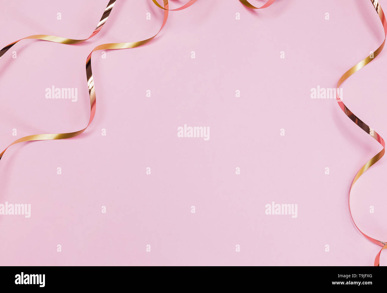 Goldene geschweifte Bänder auf den Pastell rosa Hintergrund isoliert. Festliche Kulisse mit Kopie Raum Stockfoto