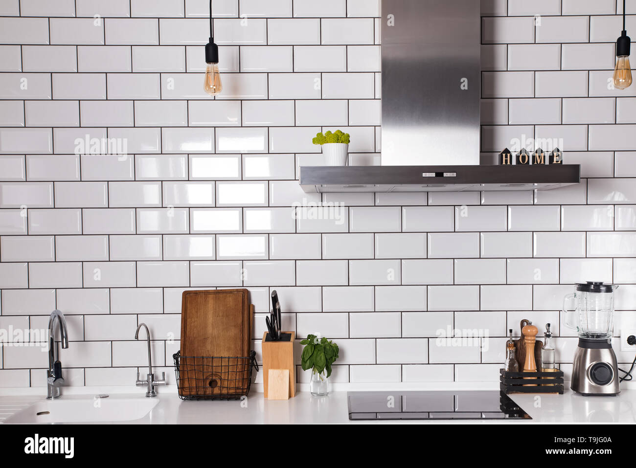 Moderne Küche mit Ziegel weiße Fliesen an der Wand und verschiedenen  Utensilien auf dem Tisch Stockfotografie - Alamy