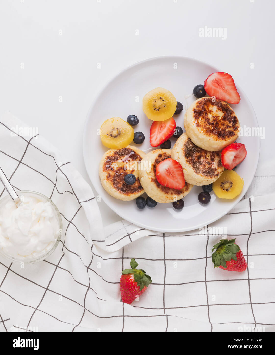 Hüttenkäse pankeas mit Beeren auf dem weißen Teller Draufsicht Stockfoto