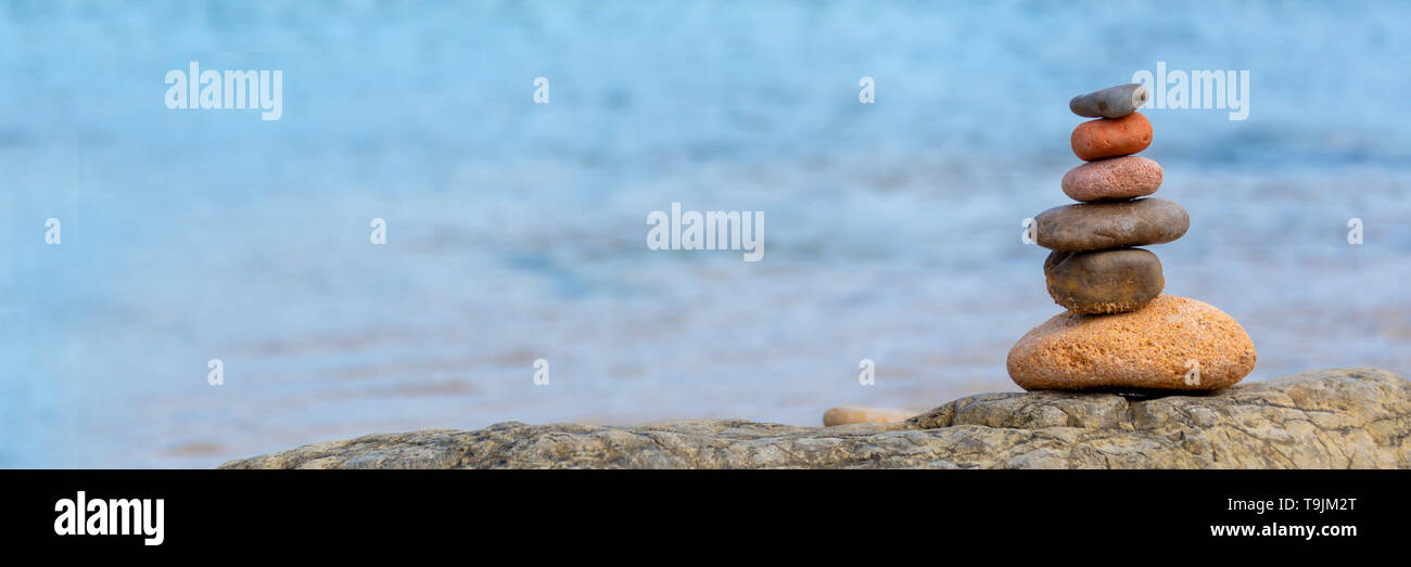 Haufen Kieselsteine am Strand, Panoramablick auf das blaue Wasser Hintergrund Stockfoto
