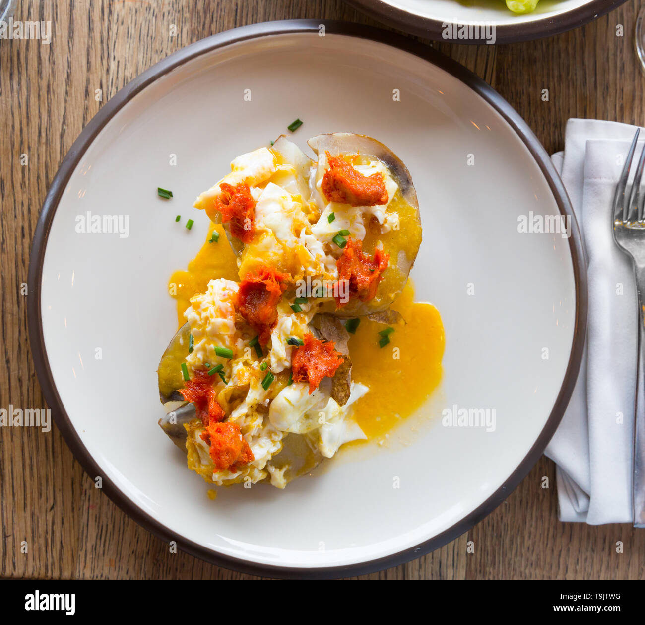 Ember - gebackene Kartoffel mit würzigen Wurst, Pastete und Eier, an Platte im Cafe Stockfoto