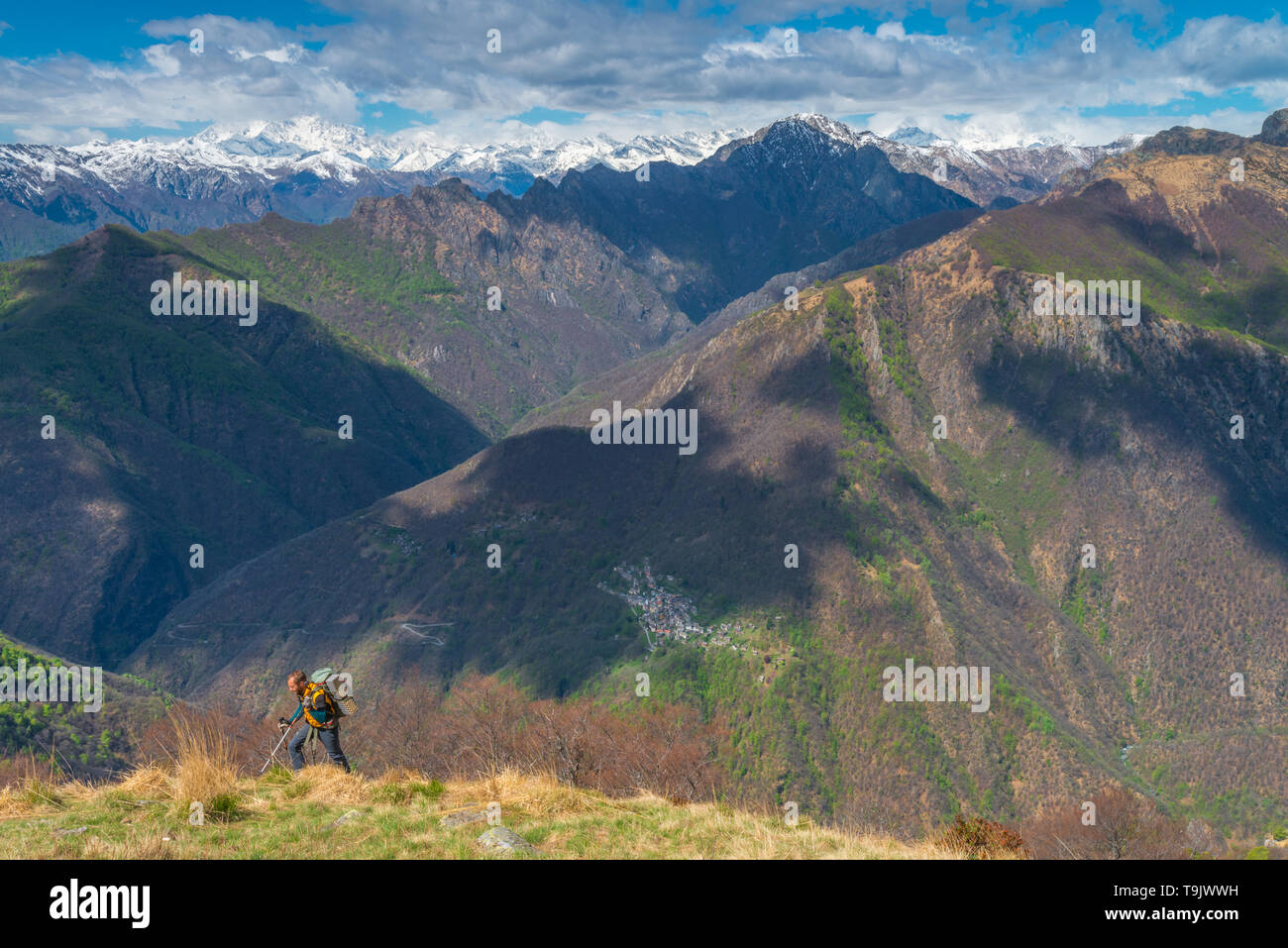 Männliche Wanderer, Wandern, Backpacker, männliche Trekker bis Wandern auf dem Berg. Schneebedeckte Berge im Hintergrund. Wanderer gegen Berge im Hintergrund. Stockfoto