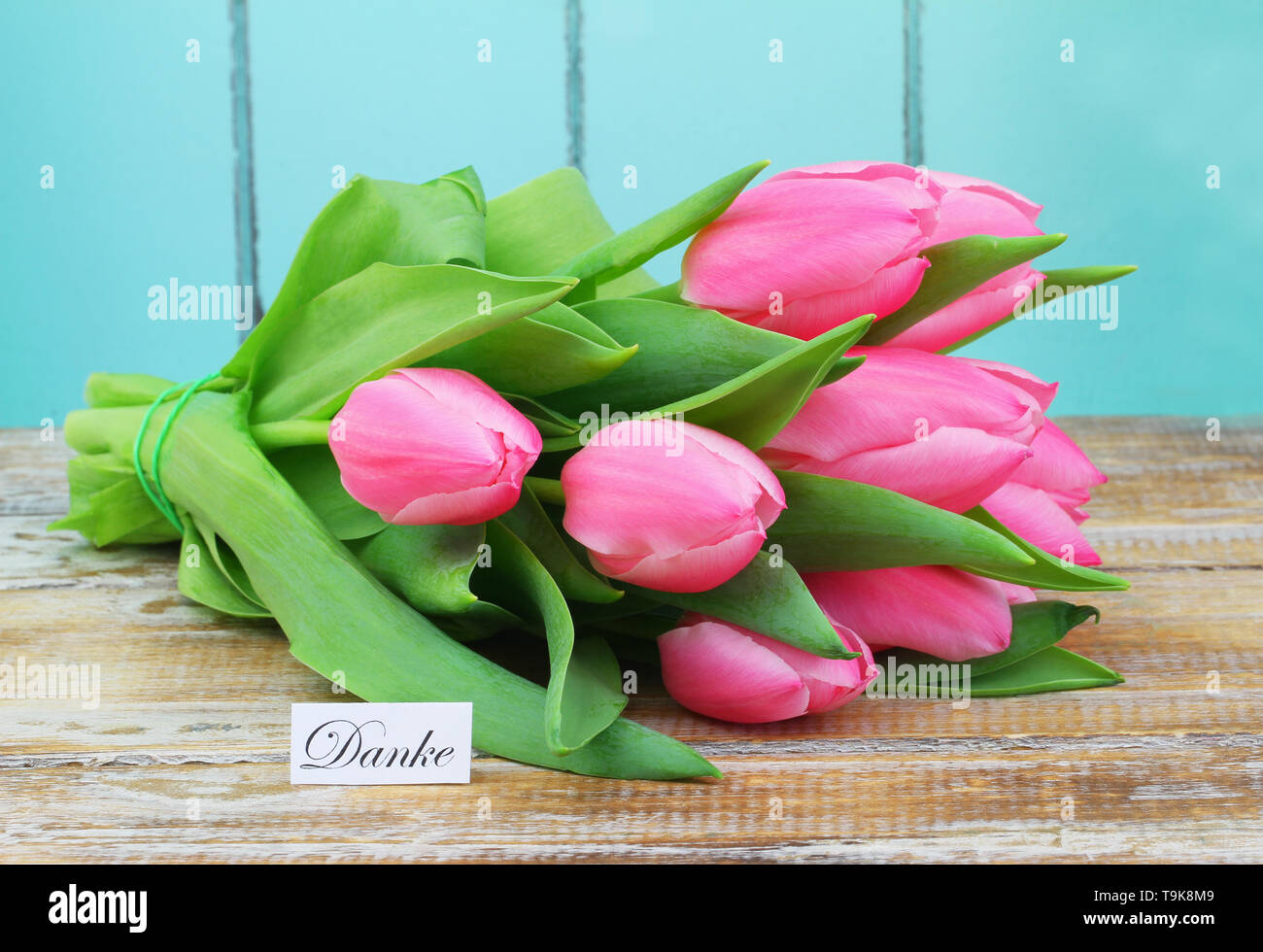 Danke (Vielen Dank, dass Sie sich in Deutscher Sprache) Karte mit Bündel von rosa Tulpen auf Holz- Oberfläche Stockfoto