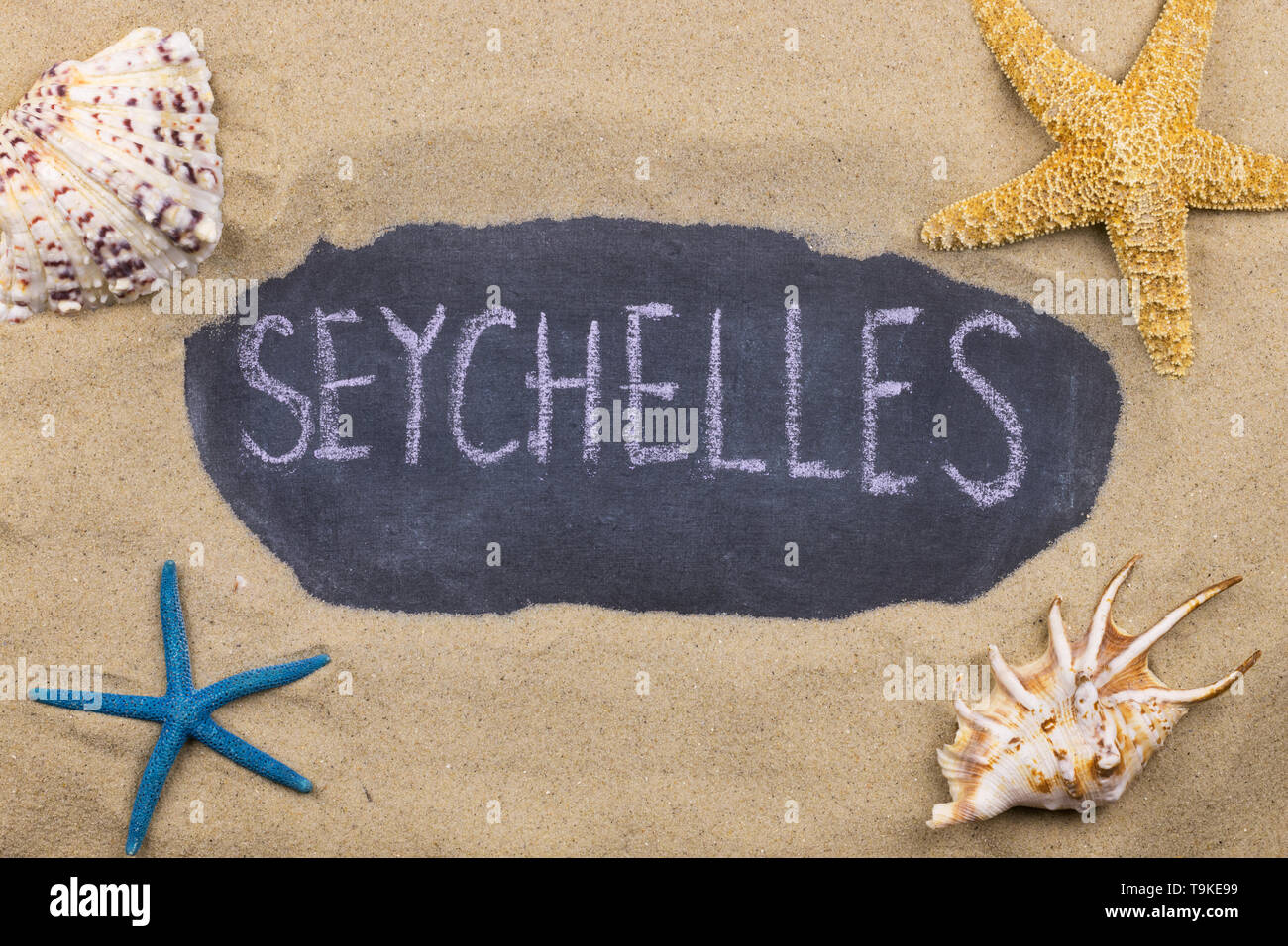 Handschriftliche Wort Seychellen mit Kreide geschrieben, unter Muscheln und Seesterne. Ansicht von oben Stockfoto