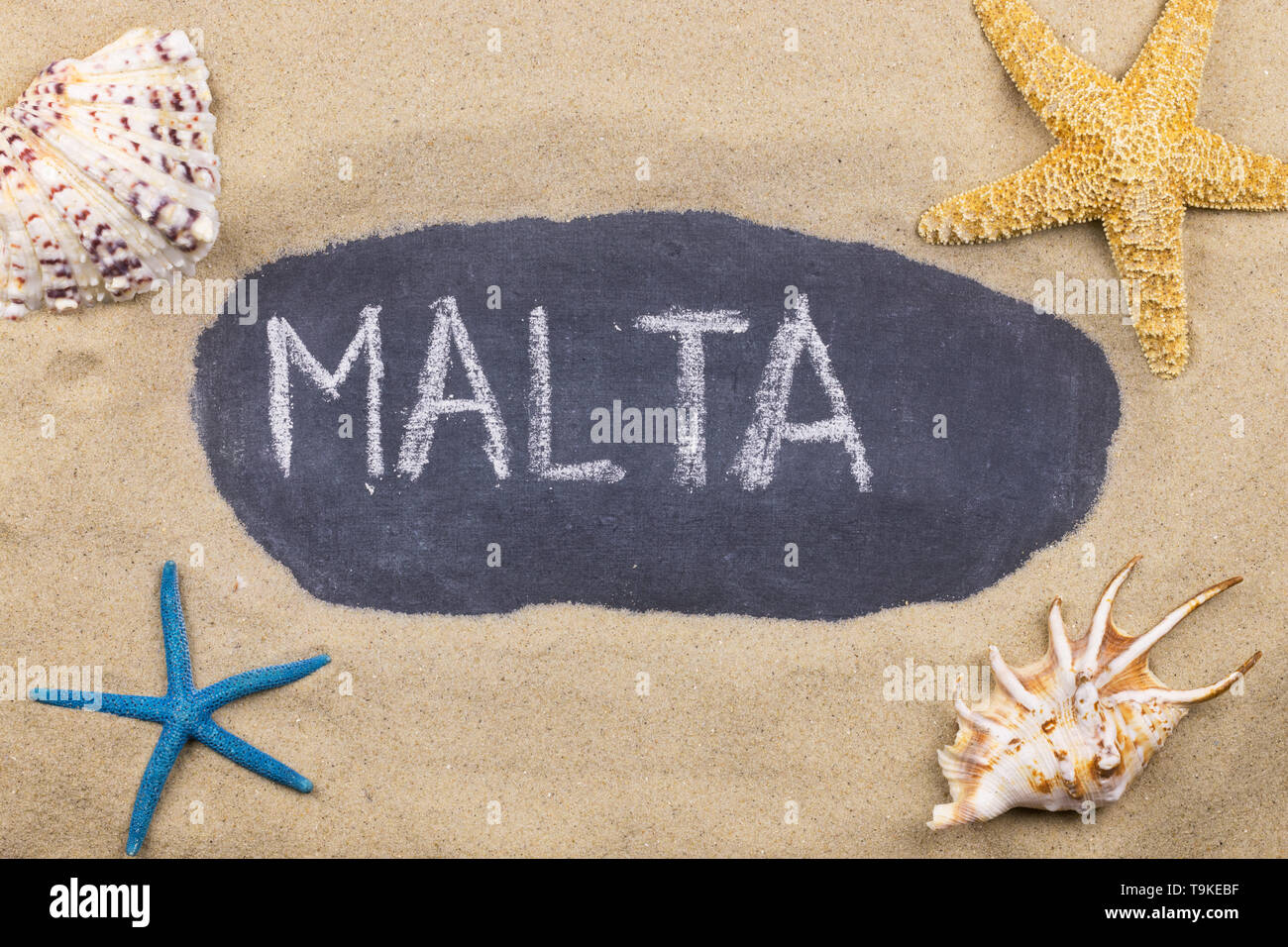 Handschriftliche Wort MALTA mit Kreide geschrieben, unter Muscheln und Seesterne. Ansicht von oben Stockfoto