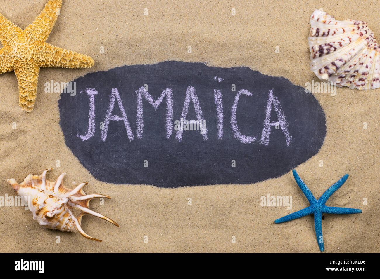 Handschriftliche Wort Jamaika mit Kreide geschrieben, unter Muscheln und Seesterne. Ansicht von oben Stockfoto