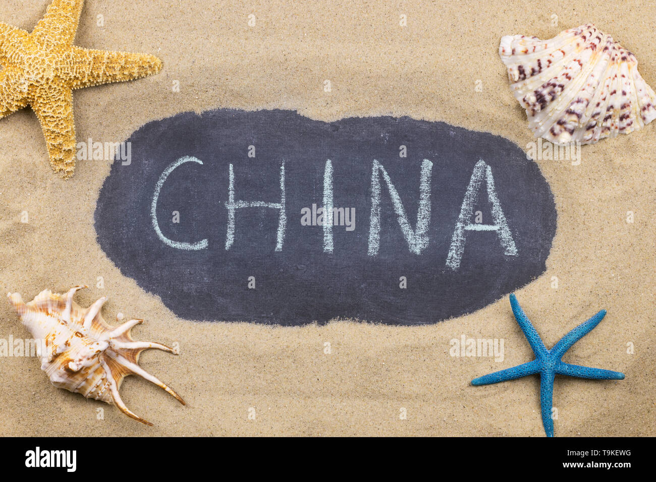 Handschriftliche Wort CHINA mit Kreide geschrieben, unter Muscheln und Seesterne. Ansicht von oben Stockfoto