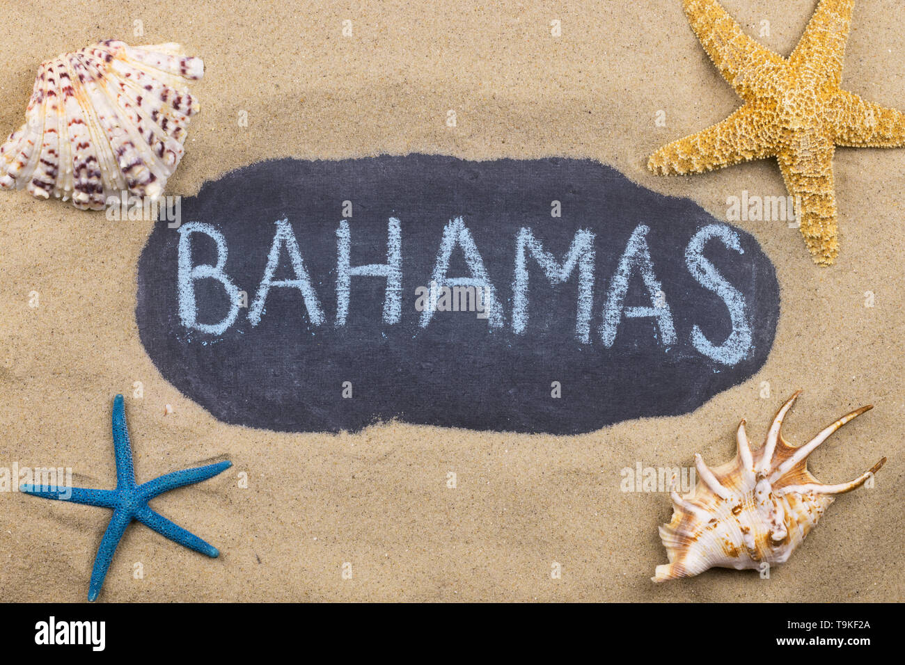 Handschriftliche Wort BAHAMAS mit Kreide geschrieben, unter Muscheln und Seesterne. Ansicht von oben Stockfoto