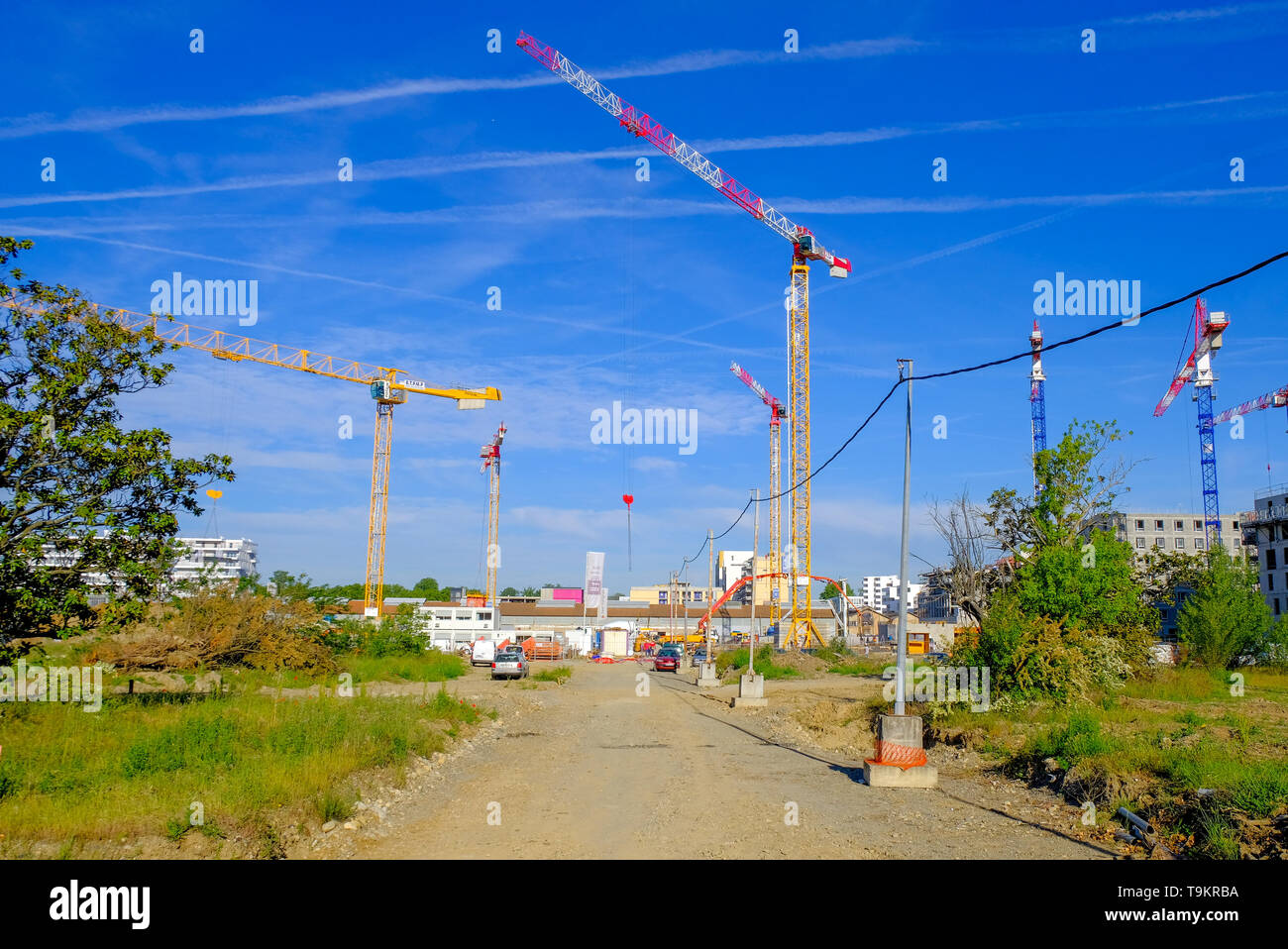 Mehrere Krane in Residential Apartment Complex Baustelle gegen den blauen Himmel mit Flugzeugen emission Streifen, Toulouse, Frankreich Stockfoto