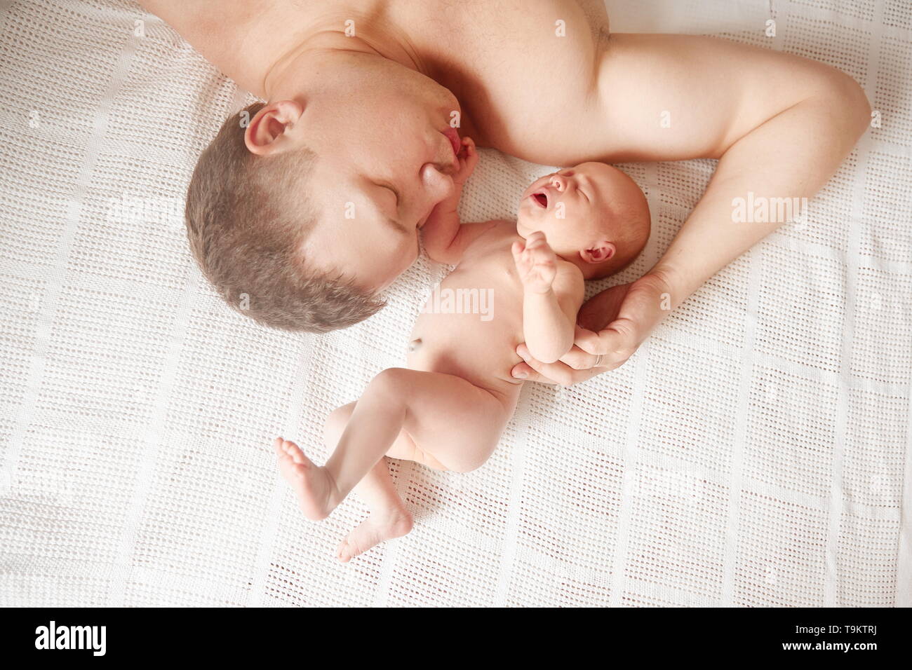Vater mit seiner neugeborenen Tochter schlief auf dem Bett. Das Konzept der väterlichen Liebe Stockfoto