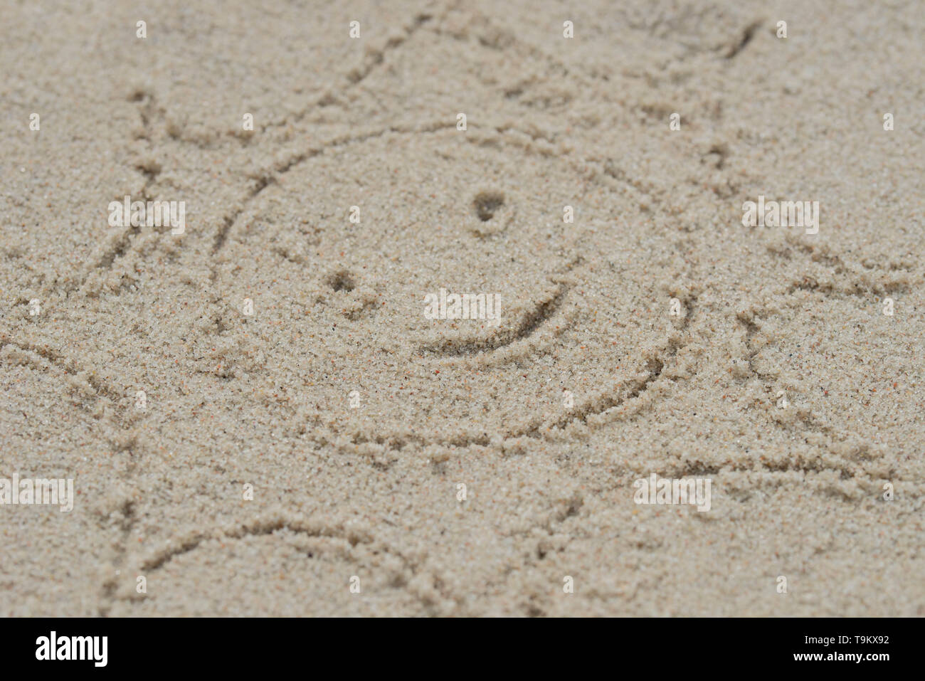 Lächelnde Sonne auf Sand Zeichnung closeup Stockfoto