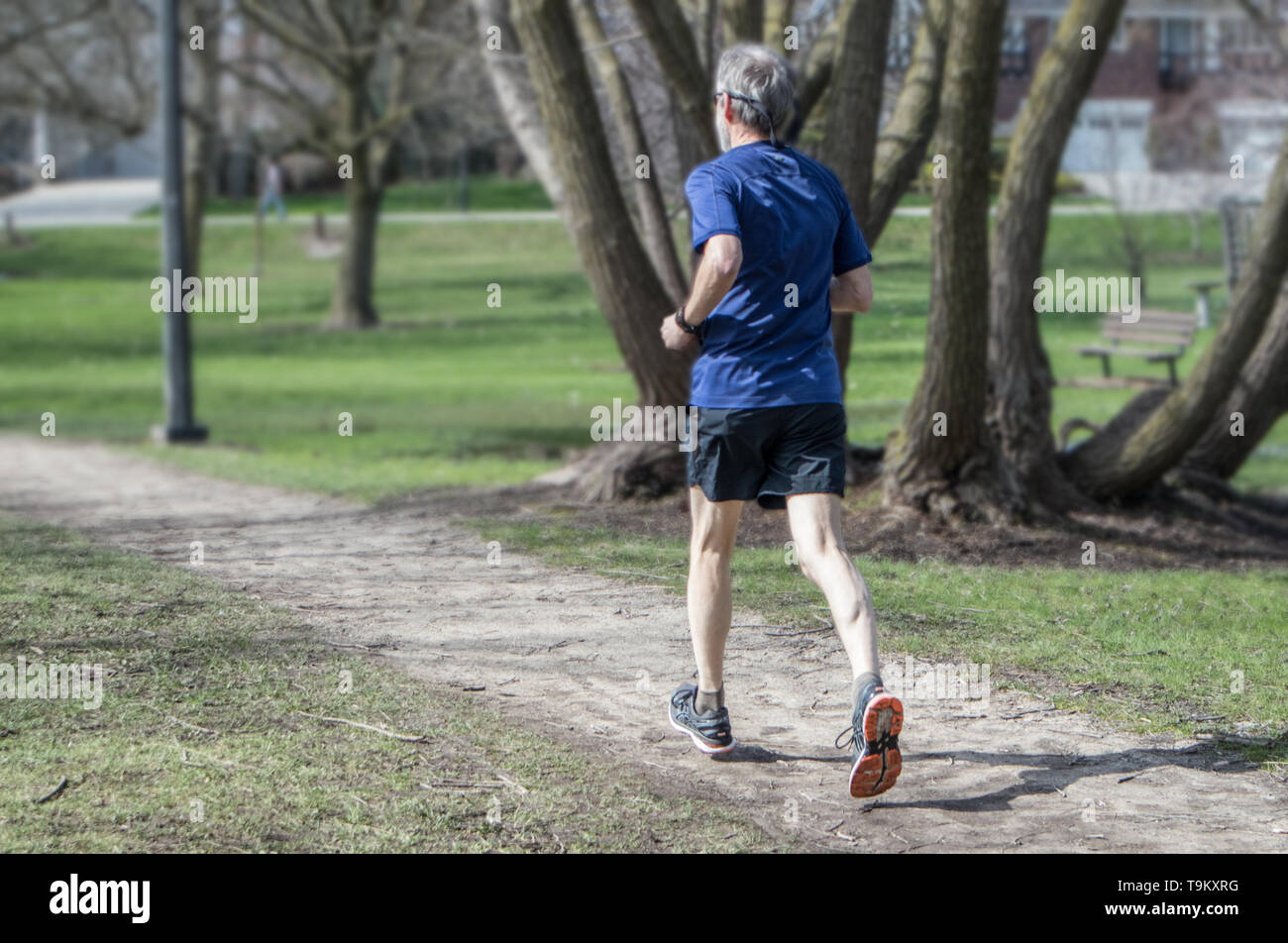 Ein älterer Mann joggt durch den Park. Ansicht von hinten. Stockfoto