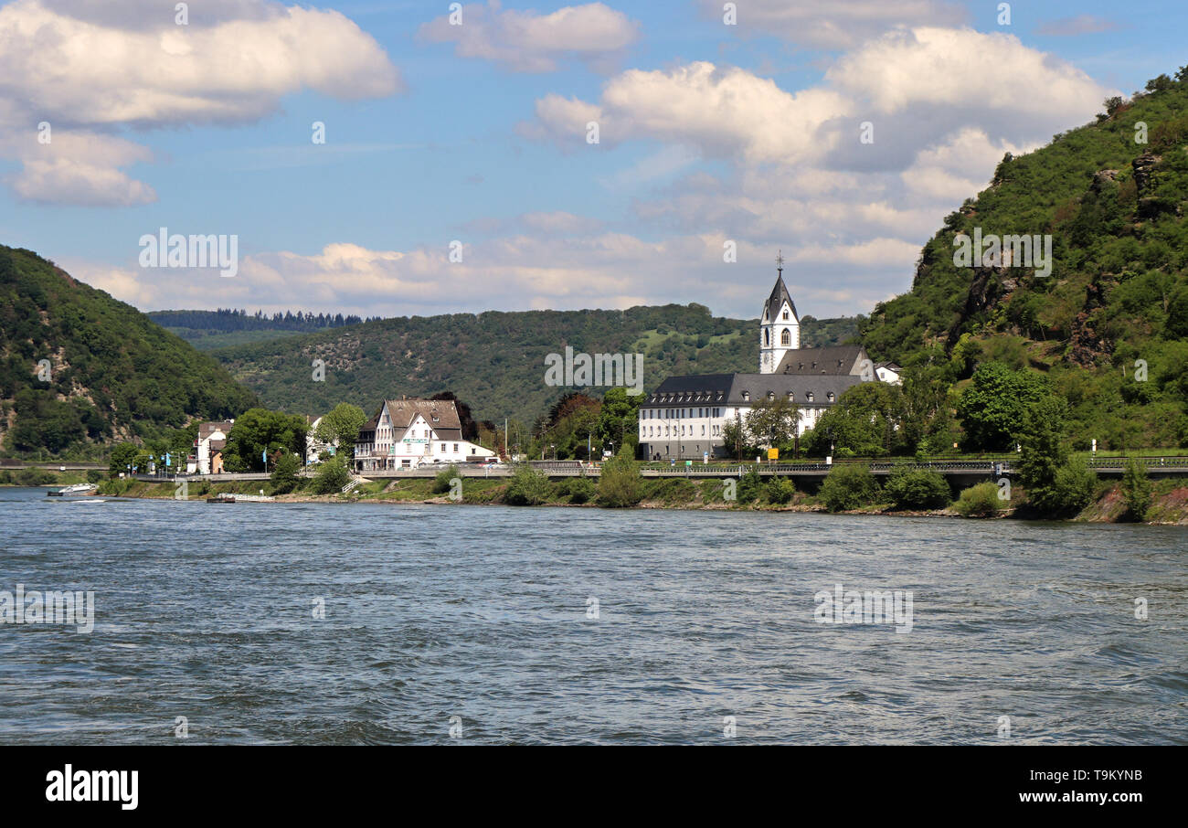 Riverside Dorf am Rhein in Deutschland mit Bäumen bedeckten Hügeln im Hintergrund Stockfoto