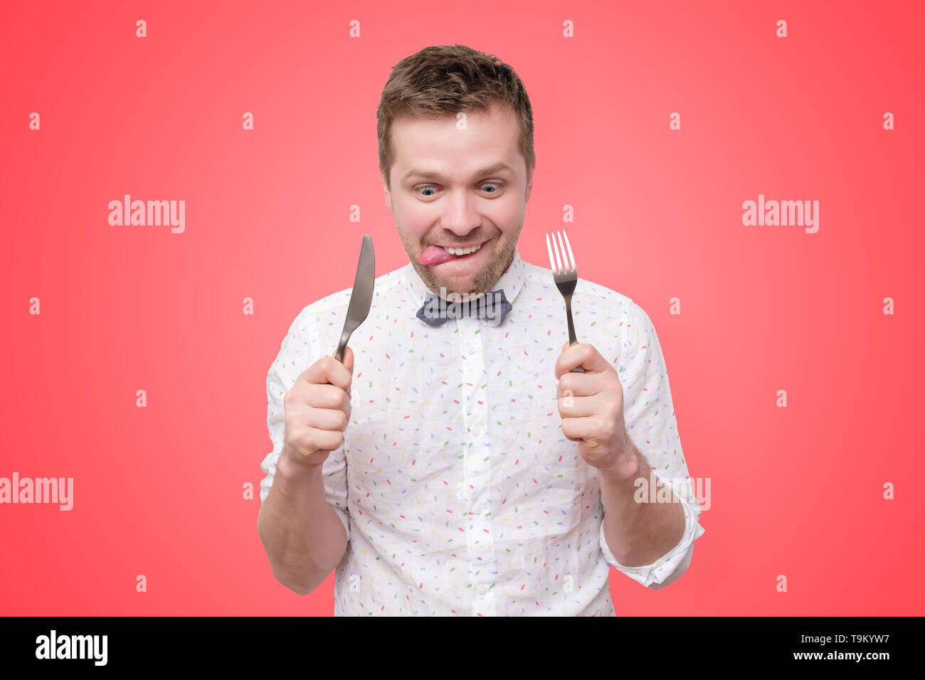 Mann mit Messer und Gabel in der Hand bereit zu essen, lecken Lippen Stockfoto