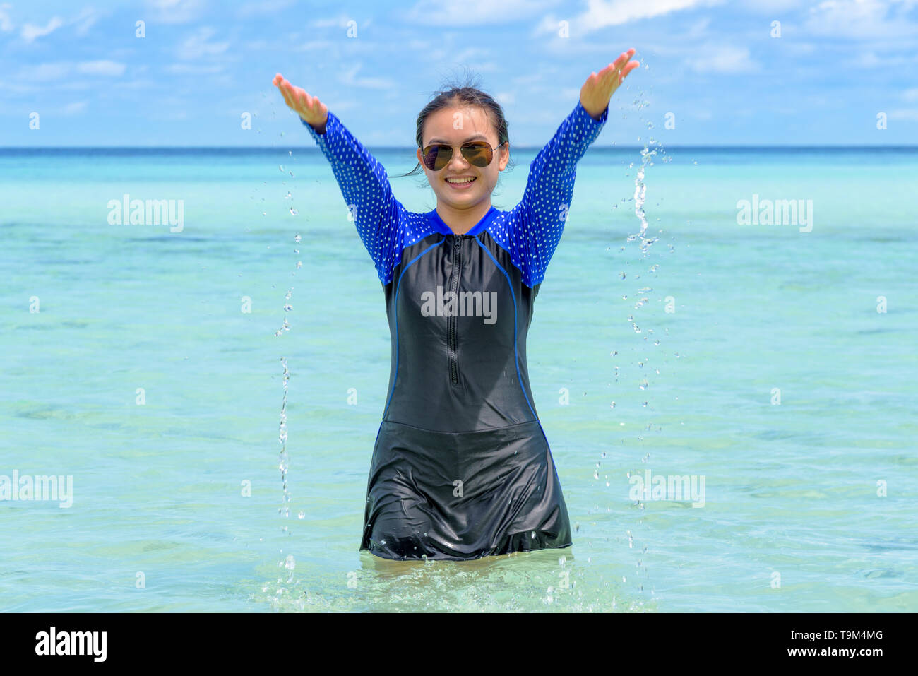 Gerne asiatische jugendlich Mädchen im Badeanzug spielen Spritzwasser in das Meer mit Spaß unter dem blauen Himmel von Ko Ra Wi auf Tour Urlaub Sommer Urlaub auf Ko Lipe Stockfoto
