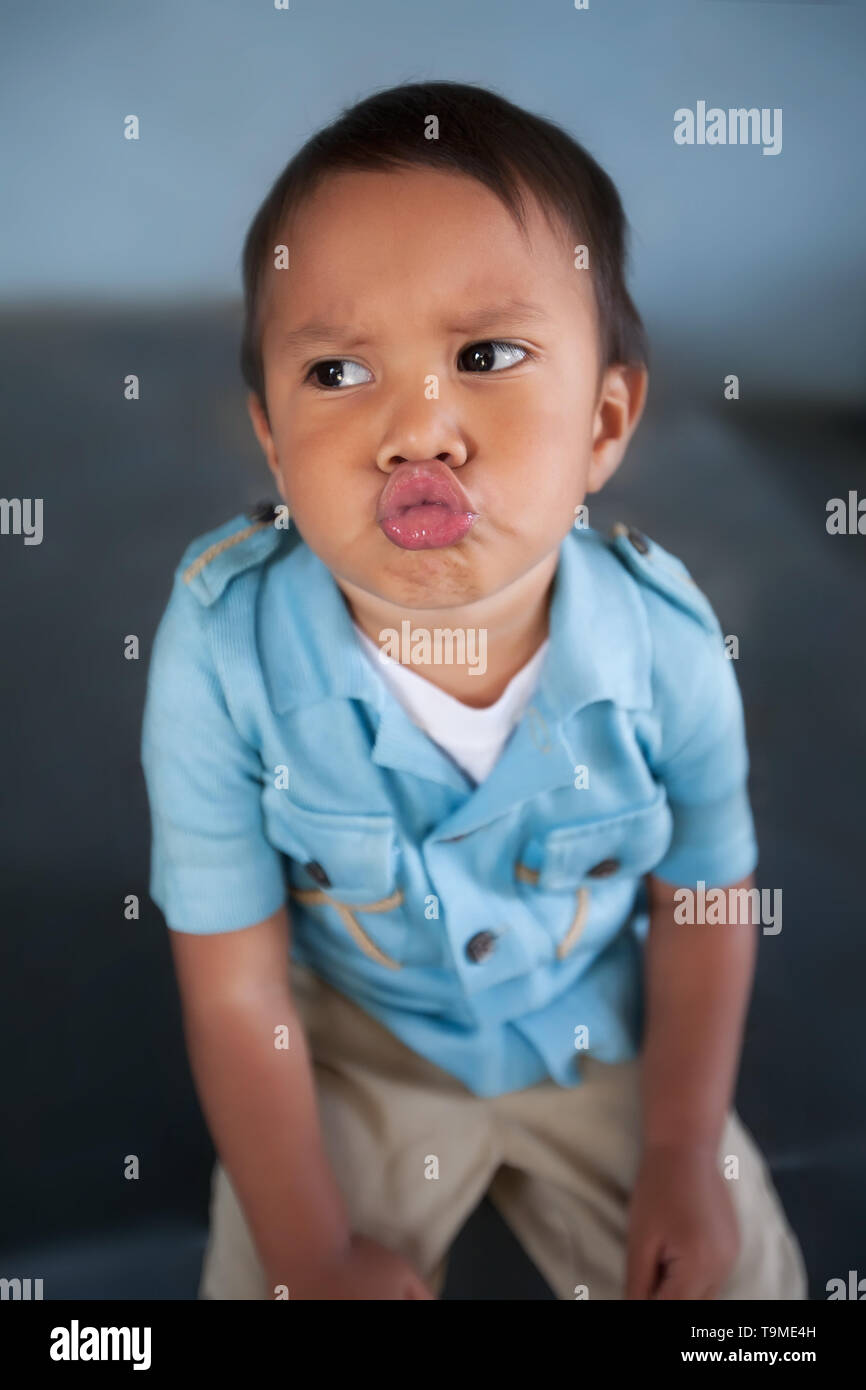 Ein Junge weg schauen mit Lippen, die mit einem Moody Ausdruck verzog, während Sie sitzen. Stockfoto