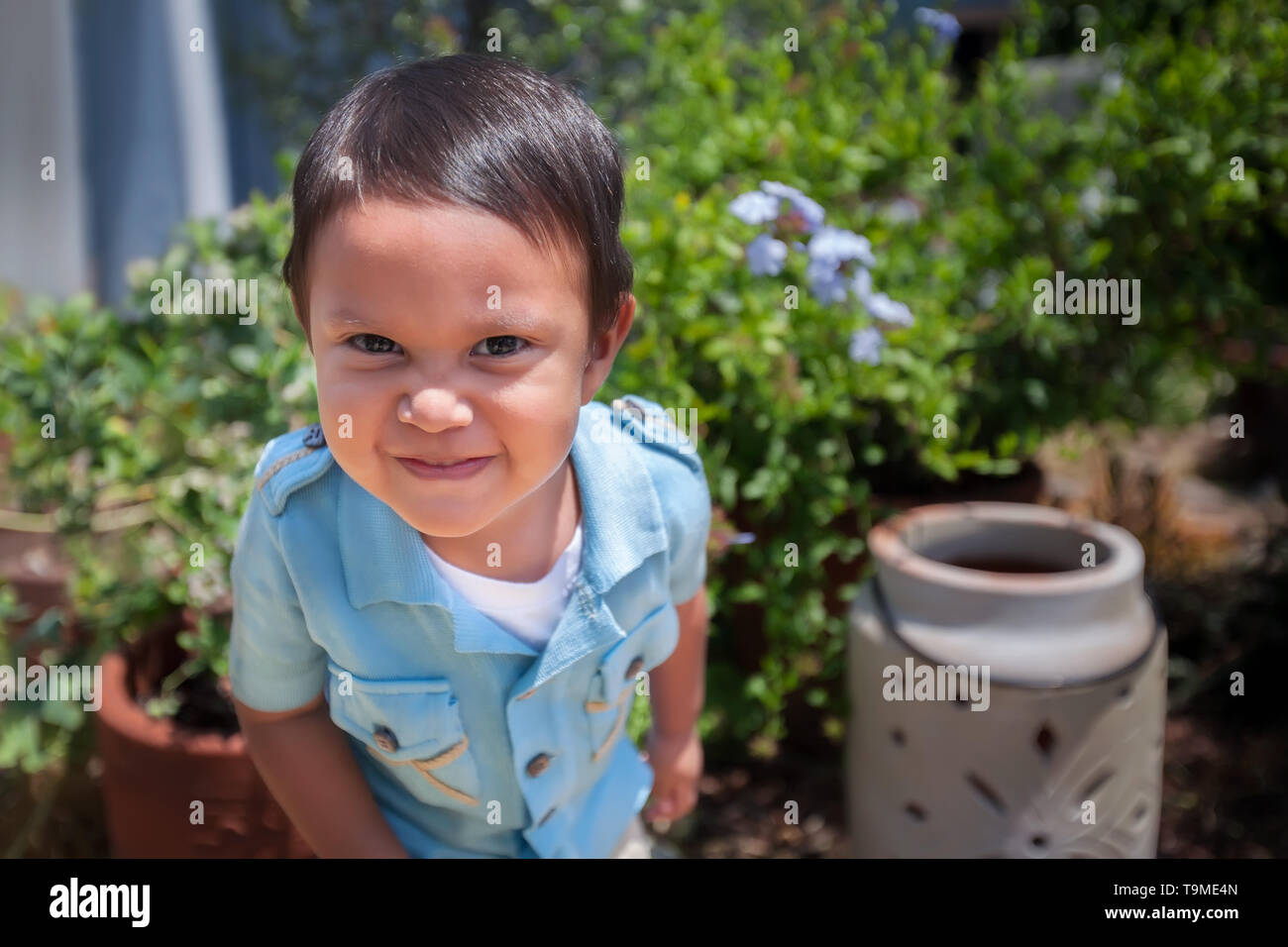 2 Jahre alten Jungen tragen ein Vintage blaues Hemd in einem Garten im Hinterhof. Stockfoto