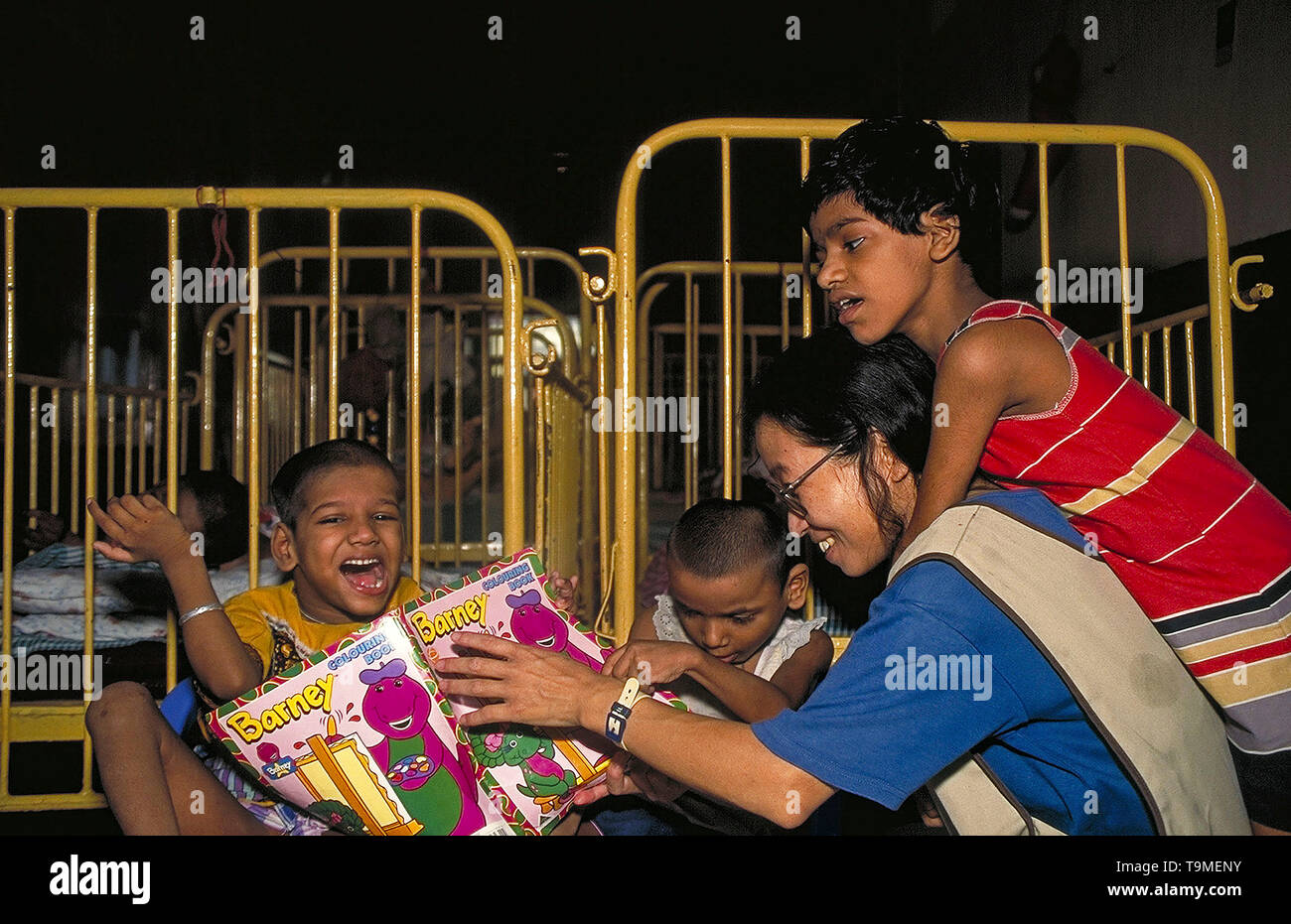 Mutter Teresa freiwilligen Lesen von einem Barney Malbuch für behinderte Kinder im Waisenhaus in Kolkata, Indien Stockfoto