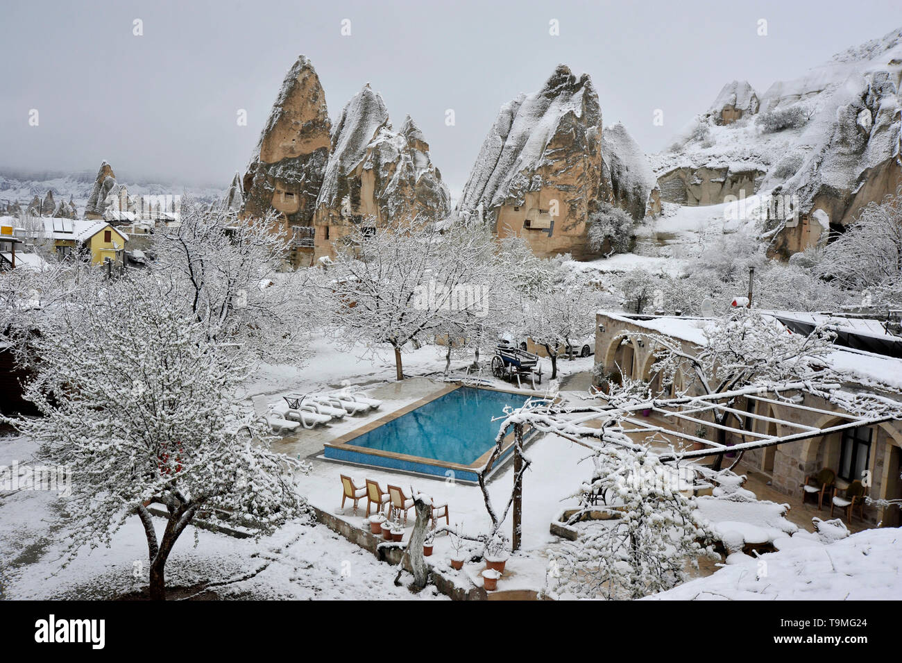 Schwimmbad und ungewöhnliche Natursteinformationen mit Schnee in Goreme in der Region Kappadokien in der Türkei Stockfoto