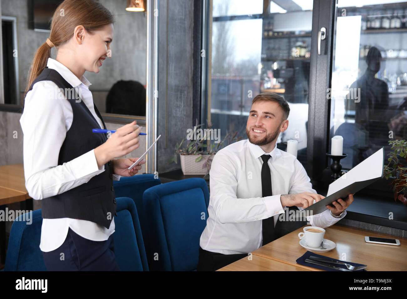 Junge Kellnerin, die einen Auftrag von Mann im Restaurant Stockfoto