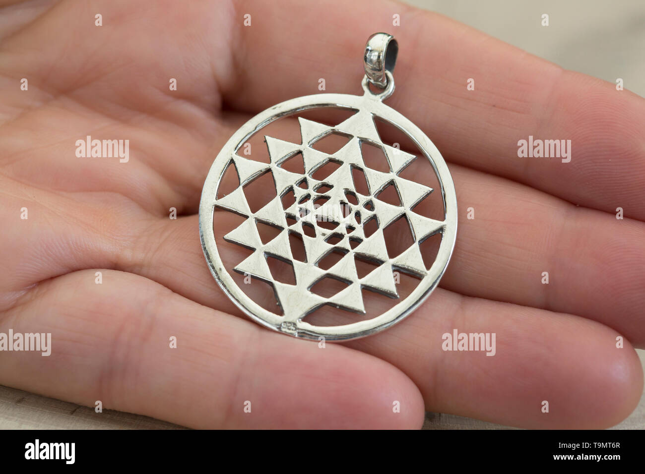 Silber sri Yantra Anhänger auf weibliche Hand Makro Detail Stockfoto