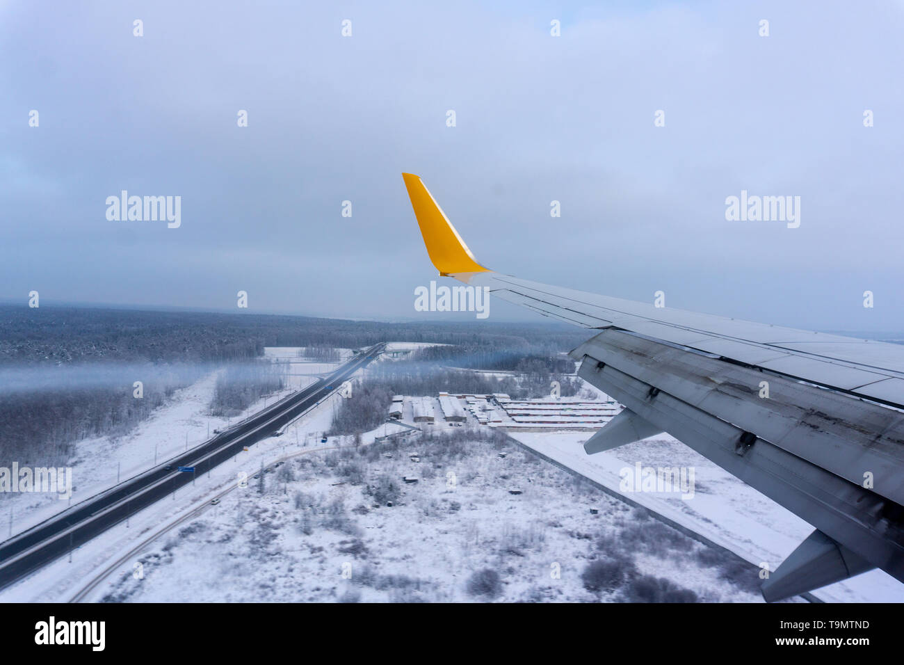 Schnee Land und Cloud durch das Fenster gesehen, Flugzeug volle Klappen der Flügel aus dem Fenster Stockfoto
