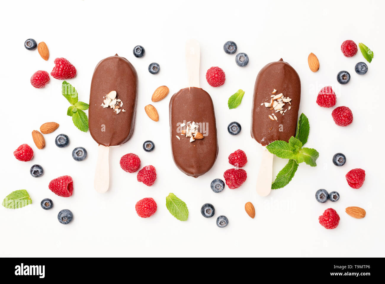 Schokoladeneis Pops und Beeren flach auf weißem Hintergrund legen. Tabelle Ansicht von oben. Sommer Konzept Stockfoto